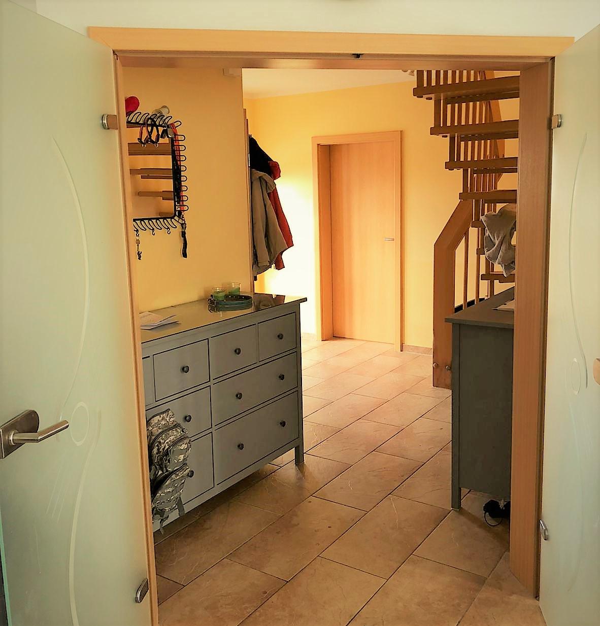 Blick vom Wohnzimmer in die helle Diele mit Bürozugang und Treppenaufgang